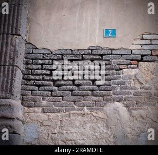 Mur gris dépressif avec plâtre écaillé, tons subdués mur d'image de brique, perspective à angle bas. Banque D'Images