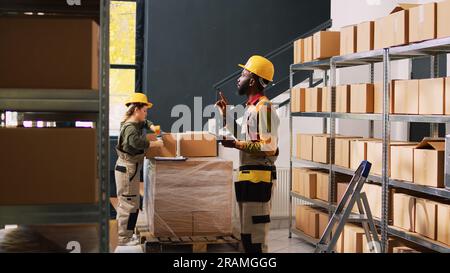 Superviseur de dépôt masculin examinant les marchandises sur tablette, travaillant sur le développement de petites entreprises. Jeune gestionnaire effectuant la vérification de la marchandise avec des produits placés sur les étagères de l'entrepôt. Banque D'Images