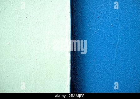 Deux tons de bandes bleues sur un mur fraîchement peint en lumière dure, centré sur deux parties égales. Banque D'Images