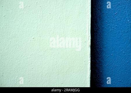 Deux tons de bandes bleues sur un mur fraîchement peint en lumière dure, décalé avec une grande pièce plus claire. Banque D'Images