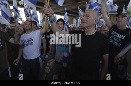 L'ancien Premier ministre Ehud Olmert détient le drapeau israélien lors d'une manifestation organisée par des manifestants anti-gouvernementaux devant le principal aéroport international d'Israël contre le Premier ministre Benjamin Netanyahu et le plan du système judiciaire du gouvernement d'extrême-droite d'Israël qui vise à affaiblir la Cour suprême du pays, À l'aéroport Ben Gurion près de tel Aviv sur 3 juillet 2023 à Lod, Israël Banque D'Images