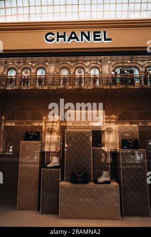 L'entrée de la boutique Chanel est chic et esthétique. Support beige neutre avec sac à main noir et chaussures blanches dans la fenêtre d'un magasin de luxe. Marque haute couture Banque D'Images