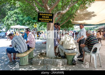 Des hommes sont assis sous un arbre annonçant de véritables fausses montres à l'entrée de l'ancien site d'Éphèse à Selcuk à Turkiye. Banque D'Images