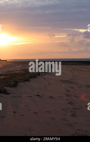 Soirée sur la plage de Botany Bay, ciel orange comme le soleil sort sous les nuages, à Broadstairs, dans le Kent, Royaume-Uni. Banque D'Images