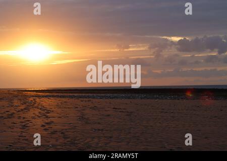 Soirée sur la plage de Botany Bay, ciel orange comme le soleil sort sous les nuages, à Broadstairs, dans le Kent, Royaume-Uni. Banque D'Images