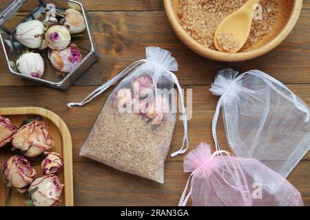 Sachet parfumé avec des roses séchées et du sel de mer sur une table en bois, pose à plat Banque D'Images