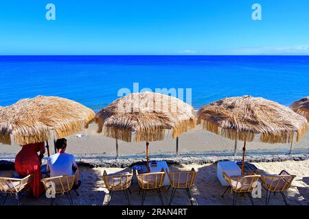 Lanzarote Îles Canaries Puerta del Carmen plage principale et palmiers et parasols en paille avec ciel bleu profond et mer Banque D'Images