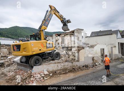 PRODUCTION - 28 juin 2023, Rhénanie-Palatinat, Mayschoß : les ouvriers utilisent une excavatrice pour niveler enfin une maison qui a été gravement endommagée par l'inondation. De nombreux bâtiments dans les villes touchées par les inondations sont encore en cours de rénovation ou attendent d'être démolis. Deux ans après la vague meurtrière des inondations, plusieurs maisons complètement détruites sont toujours debout dans la vallée de l’Ahr. Dans le même temps, de nombreux endroits sont en cours de reconstruction. La vie revient - mais lentement. (À dpa : 'échafaudage et ruines : la reconstruction dans la vallée de l'Ahr traînes') photo : Boris Roessler/dpa Banque D'Images