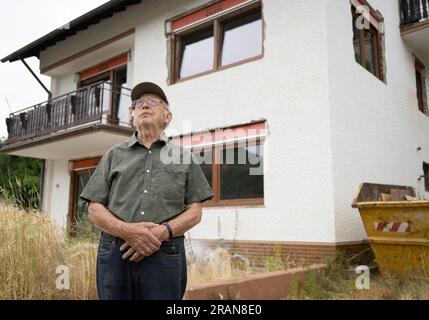 PRODUCTION - 28 juin 2023, Rhénanie-Palatinat, Dernau : Franz Kluckert, 90 ans, se tient devant sa maison sur les rives de l'Ahr. Lorsque la vague de crue est arrivée, le vieillard et sa femme avaient pu se sauver à l'étage supérieur à la dernière minute. Maintenant, il espère être en mesure de retourner bientôt dans sa maison. Deux ans après la vague meurtrière des inondations, plusieurs maisons complètement détruites sont toujours debout dans la vallée de l’Ahr. Dans le même temps, des travaux de construction sont en cours dans de nombreux endroits. La vie revient - mais lentement. (À dpa: "Échafaudage et ruines : reconstruction dans la vallée de l'Ahr traînée Banque D'Images