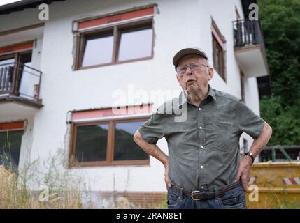 PRODUCTION - 28 juin 2023, Rhénanie-Palatinat, Dernau : Franz Kluckert, 90 ans, se tient devant sa maison sur les rives de l'Ahr. Lorsque la vague de crue est arrivée, le vieillard et sa femme avaient pu se sauver à l'étage supérieur à la dernière minute. Maintenant, il espère être en mesure de retourner bientôt dans sa maison. Deux ans après la vague meurtrière des inondations, plusieurs maisons complètement détruites sont toujours debout dans la vallée de l’Ahr. Dans le même temps, des travaux de construction sont en cours dans de nombreux endroits. La vie revient - mais lentement. (À dpa: "Échafaudage et ruines : reconstruction dans la vallée de l'Ahr traînée Banque D'Images