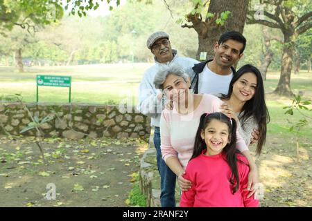 Grands-parents profitant avec petite-fille dans le parc, entouré de verdure et de sérénité. Ils passent du temps joyeux et joyeux ensemble dans les verts. Banque D'Images