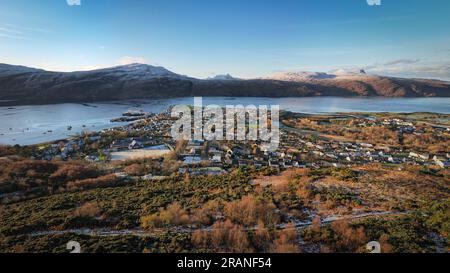 Vue aérienne d'Ullapool par une journée ensoleillée d'hiver, mettant en valeur ses montagnes enneigées et son port Banque D'Images