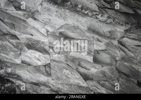 Fragment d'un mur de pierre ou d'une falaise rocheuse en gros plan. Fond abstrait naturel de roche de pierre. Banque D'Images