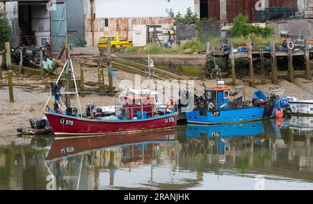 Amarré ou amarré de petits bateaux de pêche ou bateaux de pêche sur la rivière Arun à marée basse à Littlehampton, West Sussex, Angleterre, Royaume-Uni. Banque D'Images