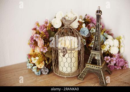Décoration maison Tour Eiffel, bougie LED et fleur artificielle sur fond de baie en bois Banque D'Images