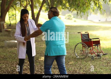 Médecin indien féminin prenant soin du patient âgé dans le jardin de l'hôpital. Le patient est incapable de marcher Banque D'Images