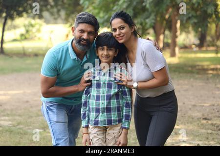 Famille indienne heureuse de père, mère, fils et une fille s'amusant dans le parc vert dans une journée dans un environnement vert et frais. Banque D'Images