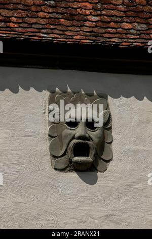 Affrontez les murs défensifs médiévaux entourant Rothenburg ob der Tauber, Bavière, Allemagne, conçus pour permettre aux défenseurs de verser du poix chaud ou de l'huile, à travers les trous d'oeil et la bouche, sur les attaquants tentant d'assiéger la ville. Le masque est à côté d'une entrée nord fortifiée de la fin des années 1300 de notre ère à la vieille ville, la porte Klingentor. Banque D'Images