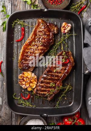 Steak striploin grillé avec des épices et des herbes sur la poêle de fer grillée. Le steak strip, également appelé une bande de New York. Banque D'Images
