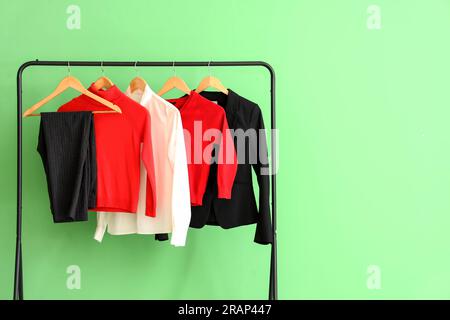 Uniforme scolaire élégant accroché sur un rack près du mur vert dans la chambre Banque D'Images