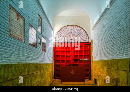 Séville, Espagne - 20 janvier 2023 : couloir menant à une porte rouge dans le bâtiment des arènes. Le couloir est entouré de murs. Banque D'Images