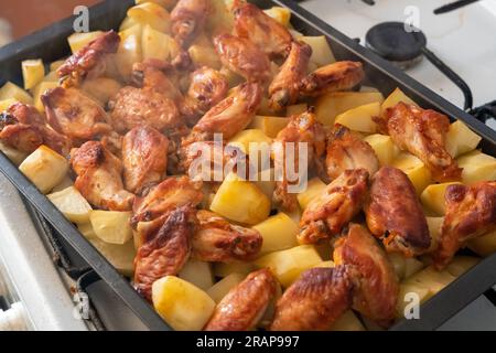 Pommes de terre vapeur fraîchement rôties avec ailes de poulet dans un moule à pâtisserie en métal Banque D'Images