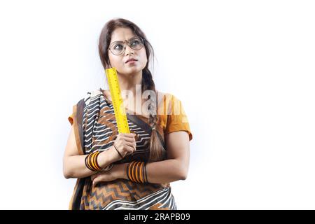 Femme heureuse indienne rurale enseignante dans le village tenant l'échelle jaune, portant Saree et spectacle dépeignant diverses expressions de la vie de l'enseignant. Banque D'Images