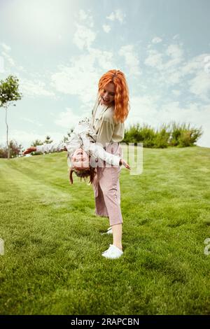 Joyeux week-ends. Belle rousse jeune femme, mère jouant avec sa petite fille dans le parc sur la chaude journée d'été Banque D'Images