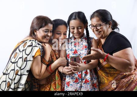 Rurales indiennes femmes heureuses à Saree prenant selfie et faisant un appel vidéo dans un village. Une jeune fille tient un téléphone portable Banque D'Images