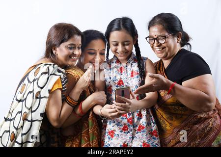 Rurales indiennes femmes heureuses à Saree prenant selfie et faisant un appel vidéo dans un village. Une jeune fille tient un téléphone portable Banque D'Images