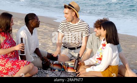 Groupe d'adolescents multi-ethniques sur la plage s'amusant tout en buvant de la bière. Vacances d'été, fête sur la plage Banque D'Images