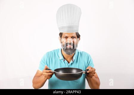 Portrait d'un chef barbu indien portant un t-shirt et une casquette de chef. Heureux souriant expressions fond blanc. Tenir la spatule et la cuillère à frire dans la main Banque D'Images