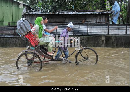 Les gens font leur chemin pendant les fortes pluies. Les pluies incessantes de ces derniers jours ont causé des problèmes d’engorgement à travers Sylhet, avec de nombreuses routes submergées. En raison d'un développement non planifié et d'un système de drainage médiocre, ces zones gorgées d'eau sont inondées pendant les fortes pluies et même les pluies légères, disent les habitants. Sylhet, Bangladesh. Banque D'Images