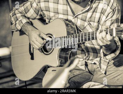 Plan rapproché d'un guitariste lors d'une performance sur scène jouant d'un instrument folk. Banque D'Images