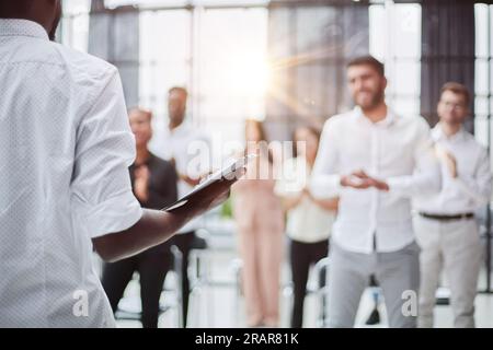 Vue en grand angle d'un groupe multiethnique de gens d'affaires qui applaudissent en se tenant debout et souriant dans le public lors d'une conférence d'affaires ou d'un séminaire, dans un espace de copie Banque D'Images
