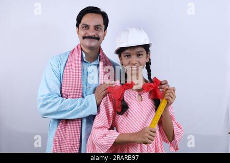 Rural indien heureux villageois père dans kurta pyjama debout avec sa fille confiante. Fille portant un casque et prête à se mettre pour un avenir brillant Banque D'Images