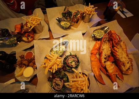 Gros plan grillé rouleau de homard et frites de pommes de terre servis avec des calamars au citron et une salade de roquette verte Banque D'Images