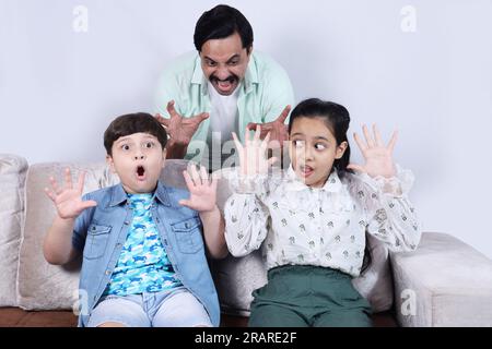 Heureuse famille indienne de père, fils et fille surfer ordinateur portable ayant un temps agréable ensemble joyeusement. La famille se penche sur l'ordinateur portable. Banque D'Images