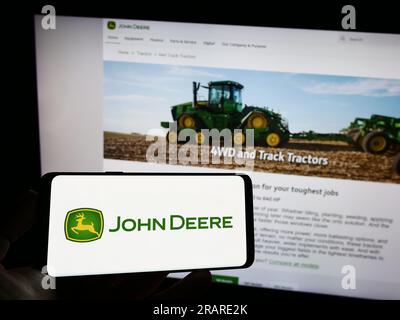 Personne tenant le téléphone portable avec le logo de l'entreprise américaine Deere and Company (John Deere) sur l'écran devant la page Web de l'entreprise. Concentrez-vous sur l'affichage du téléphone. Banque D'Images