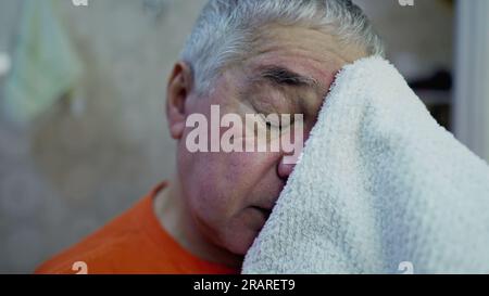 Gros plan visage d'un homme plus âgé séchant le visage après le lavage le matin Banque D'Images