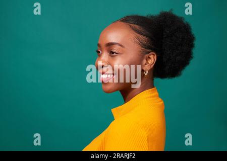 Profil de belle femme noire, fond sarcelle studio, portrait de mode Banque D'Images