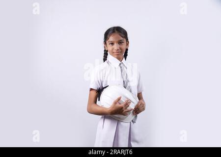 Portrait d'un enfant d'école heureux comme ouvrier de la construction. Concept futur meilleur et stable. L'écolier tient le casque du directeur de la construction en main Banque D'Images