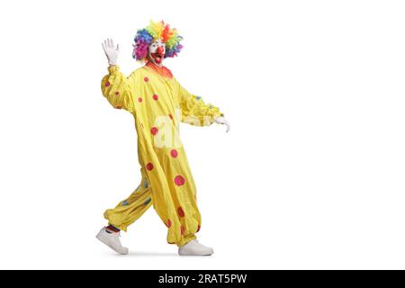 Plan complet d'un clown en costume jaune marchant et agitant isolé sur fond blanc Banque D'Images