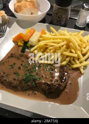 côtelette de veau avec sauce et frites sur une assiette rectangulaire en céramique blanche Banque D'Images