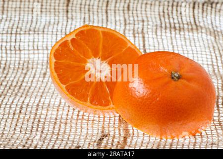 Plan rapproché en studio d'une mandarine coupée en deux sur toile de jute. Banque D'Images