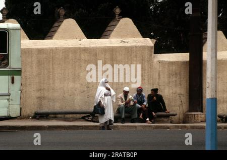 Alger Algérie scène de rue Femme portant le foulard Marche par des hommes assis sur le banc Banque D'Images