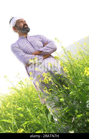 Portrait d'un fermier indien heureux sentant le vent tout en se tenant dans le champ étirant ses bras. Inde rurale. Joyeux Villager pour voir les cultures florissantes. Banque D'Images