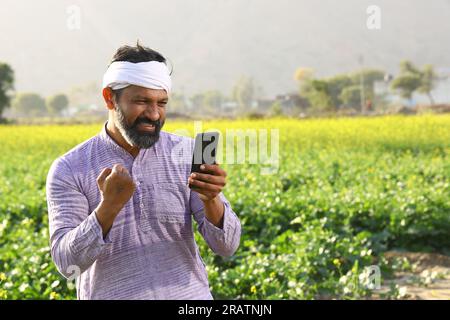 Heureux fermier indien sentant le vent tout en se tenant dans le champ en étirant ses bras. Banque D'Images