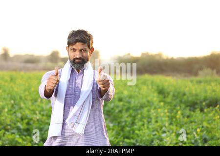 Portrait d'un fermier indien heureux sentant le vent tout en se tenant dans le champ étirant ses bras. Inde rurale. Joyeux Villager pour voir les cultures florissantes. Banque D'Images