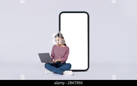 Positif jeune femme entrepreneur indépendant assis par téléphone à l'aide d'un ordinateur portable Banque D'Images